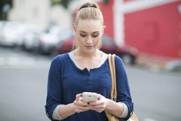 Portrait of young woman looking at her smartphone - ZEF000069