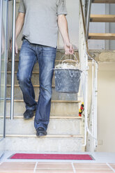 Mann trägt Eimer mit Schutt bei der Hausrenovierung - DRF001090