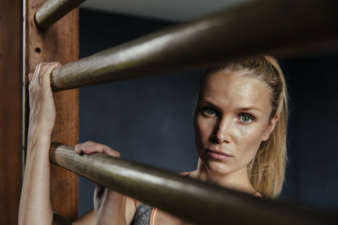 Ernste Frau an der Sprossenwand im Fitnessstudio, lizenzfreies Stockfoto