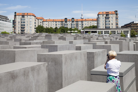 Deutschland, Berlin, Holocaust-Mahnmal, Ältere Frau fotografiert Stelen, lizenzfreies Stockfoto