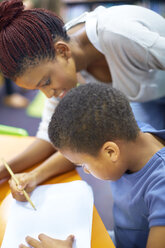Young woman teaching boy writing on paper - ZEF000753