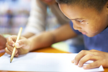 Young woman teaching boy writing on paper - ZEF000754