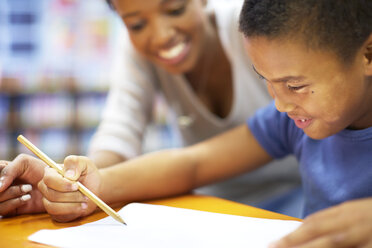 Young woman teaching boy writing on paper - ZEF000755