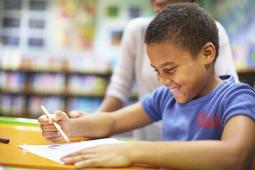 Young woman teaching boy writing on paper - ZEF000756