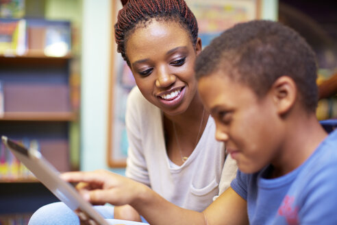 Junge Frau und Junge mit digitalem Tablet in einer Bibliothek - ZEF000189