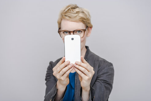 Blonde Frau macht ein Foto mit ihrem Smartphone - TCF004281
