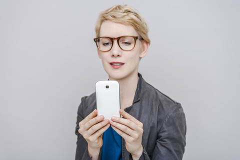 Blonde Frau macht ein Selfie mit ihrem Smartphone, lizenzfreies Stockfoto