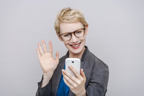 Lächelnde blonde Frau macht ein Selfie mit ihrem Smartphone - TCF004284