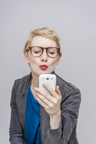 Blond woman pouting mouth taking a selfie with her smartphone stock photo