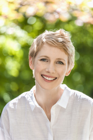 Porträt einer lächelnden Frau mit kurzen blonden Haaren, lizenzfreies Stockfoto