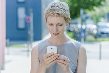 Porträt einer blonden Frau mit Smartphone - TCF004308