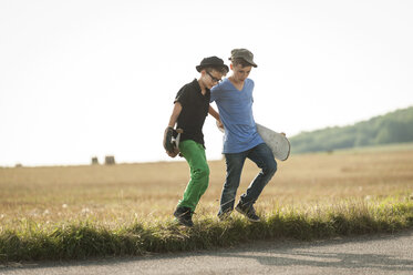Zwei Jungen laufen mit ihren Skateboards über ein Feld - PAF000883