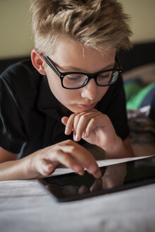 Portrait of a boy lying on bed using digital tablet - PAF000885