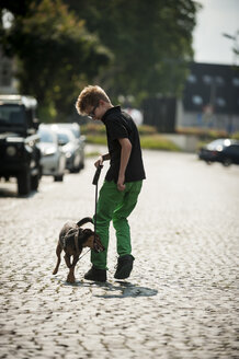 Junge geht mit seinem Hund eine Straße entlang - PAF000879