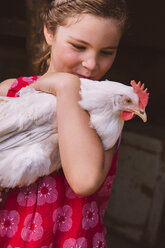 Germany, Northrhine Westphalia, Bornheim, Girl holding chicken in arms - MFF001172