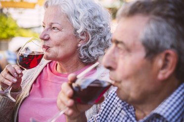 Germany, Northrhine Westphalia, Bornheim, Senior couple sitting in courtyard, drinking red wine - MFF001184