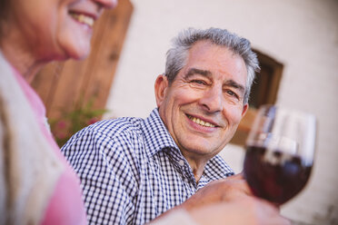 Germany, Northrhine Westphalia, Bornheim, Senior couple sitting in courtyard, drinking red wine - MFF001185