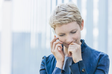 Portrait of blond woman telephoning with smartphone looking down - TCF004439