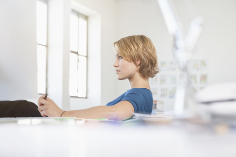 Portrait of young woman relaxing at her desk in a creative office stock photo