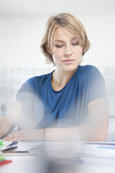 Porträt einer arbeitenden jungen Frau an ihrem Schreibtisch in einem kreativen Büro - RBF001841