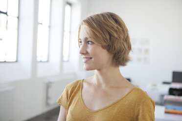 Portrait of smiling young woman in a creative office - RBF001812