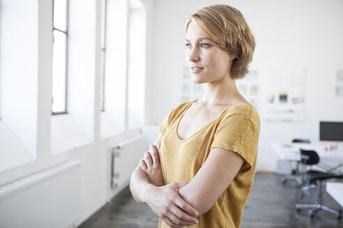 Porträt einer jungen Frau mit verschränkten Armen in einem kreativen Büro - RBF001816