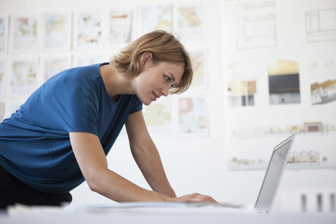 Porträt einer jungen Frau, die einen Laptop in einem kreativen Büro benutzt, lizenzfreies Stockfoto