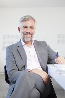 Porträt eines lächelnden Mannes an seinem Schreibtisch in einem Büro - RBF001821