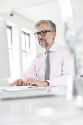 Portrait of man working at his desk in an office - RBF001823