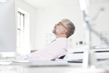Mann arbeitet entspannt an seinem Schreibtisch in einem Büro - RBF001826