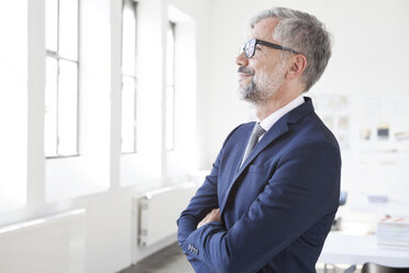 Geschäftsmann mit verschränkten Armen in einem Büro stehend - RBF001883