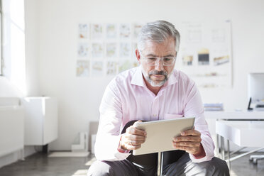 Portrait of businessman using digital tablet in an office - RBF001893