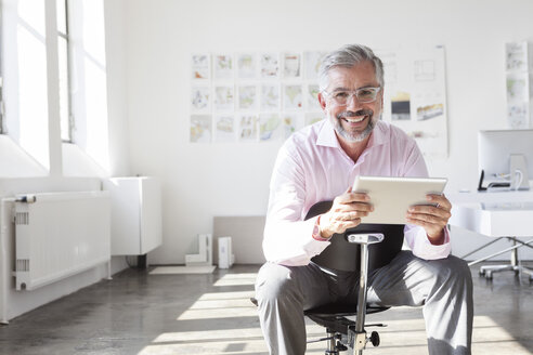 Porträt eines lächelnden Geschäftsmannes mit digitalem Tablet in einem Büro - RBF001894