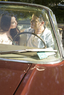 Paar sitzt in einem Oldtimer-Cabrio und schaut sich gegenseitig an - FCF000439