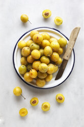 Bowl of mirabelles and a kitchen knife on white background - EVGF000820