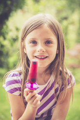 Porträt eines kleinen Mädchens mit Eis am Stiel im Garten - SARF000786