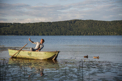 Germany, Rhineland-Palatinate, Laach Lake, Man sitting in a rowing boat and taking a selfie - PAF000904