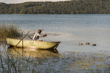 Deutschland, Rheinland-Pfalz, Laacher See, Mann sitzt in einem Ruderboot und fotografiert Enten - PAF000905