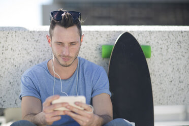 Skateboarder macht eine Pause und benutzt dabei sein Smartphone - ZEF000769