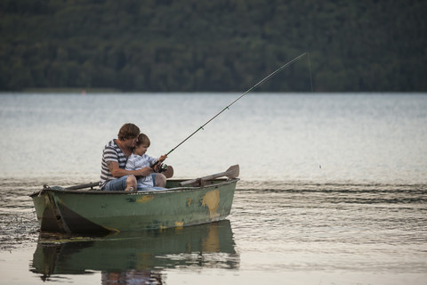 Deutschland, Rheinland-Pfalz, Laacher See, Vater und Sohn fischen vom Boot aus, lizenzfreies Stockfoto