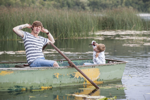 Deutschland, Rheinland-Pfalz, Laacher See, verspielter Vater und Sohn im Boot, lizenzfreies Stockfoto