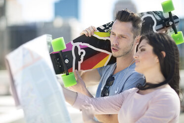 Young couple with skateboard looking at city map - ZEF000791