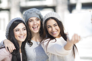 Drei Freundinnen mit Wollmützen machen ein Selfie mit digitalem Tablet - ZEF000799