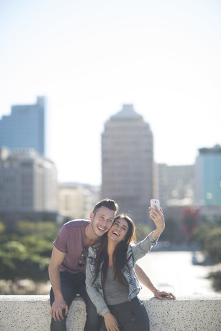 Glückliches junges Paar macht ein Selfie mit Smartphone, lizenzfreies Stockfoto