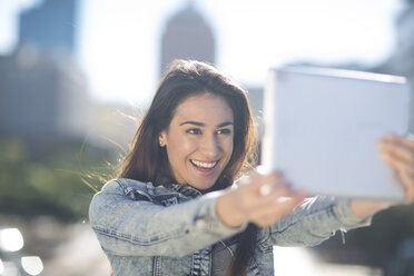 Porträt einer glücklichen jungen Frau, die ein Selfie mit einem digitalen Tablet macht - ZEF000818