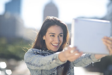 Portrait of happy young woman taking a selfie with digital tablet - ZEF000818