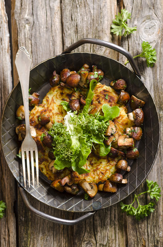 Frische Kartoffelrösti aus der Pfanne mit Champignons und Salat, lizenzfreies Stockfoto