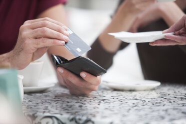 Mann bezahlt Rechnung mit Kreditkarte in einem Straßencafé - ZEF000349