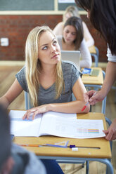 Teacher explaining something to student in classroom - ZEF000678