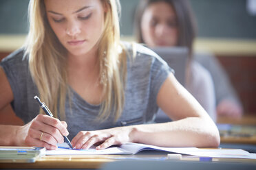 Studentin im Klassenzimmer beim Schreiben am Schreibtisch - ZEF000685